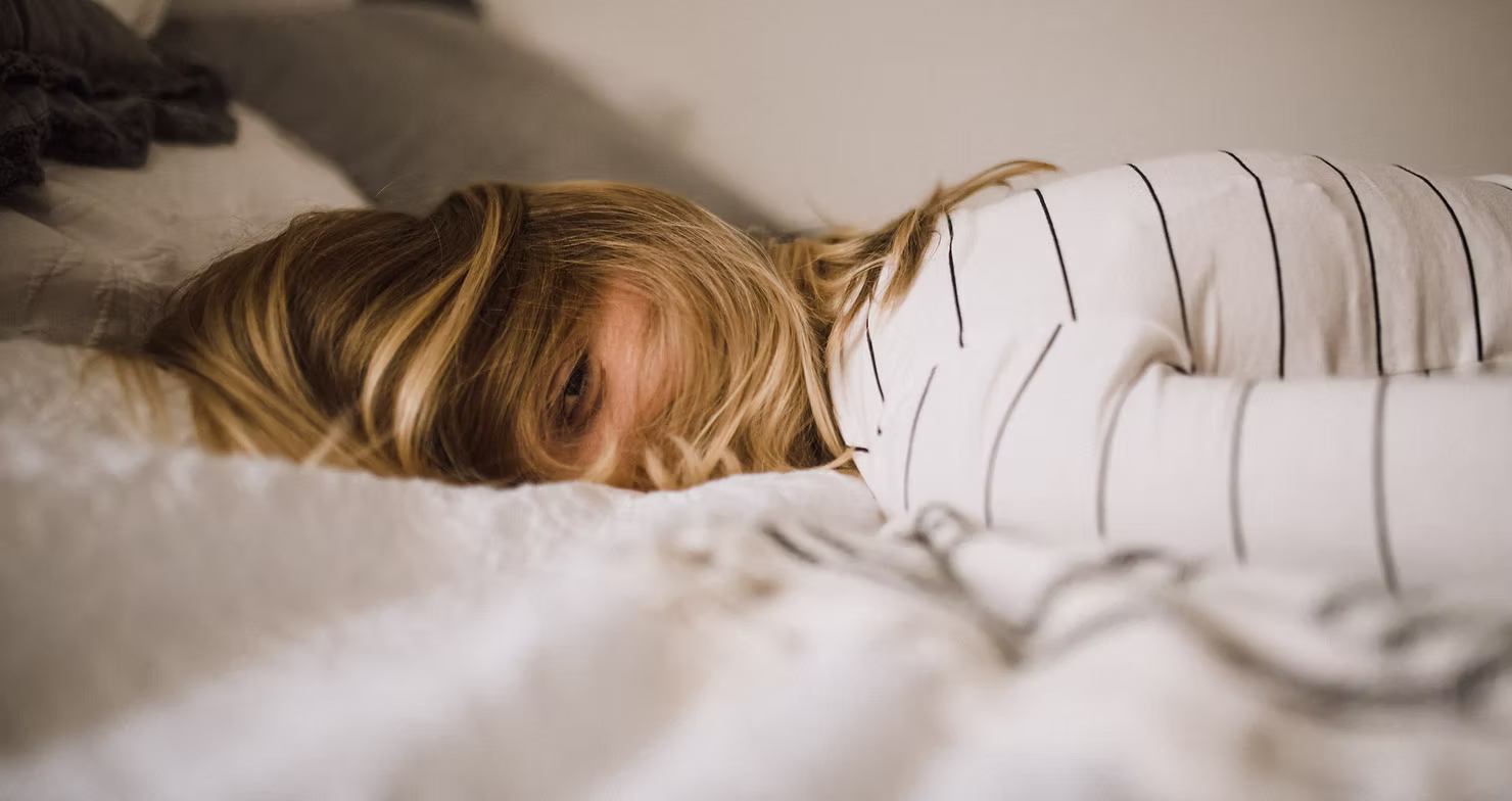 Kobieta leżąca na łóżku z trudnością z zasypianiem – problemy ze snem i naturalna regeneracja